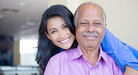 An older man with a younger lady behind him smiling