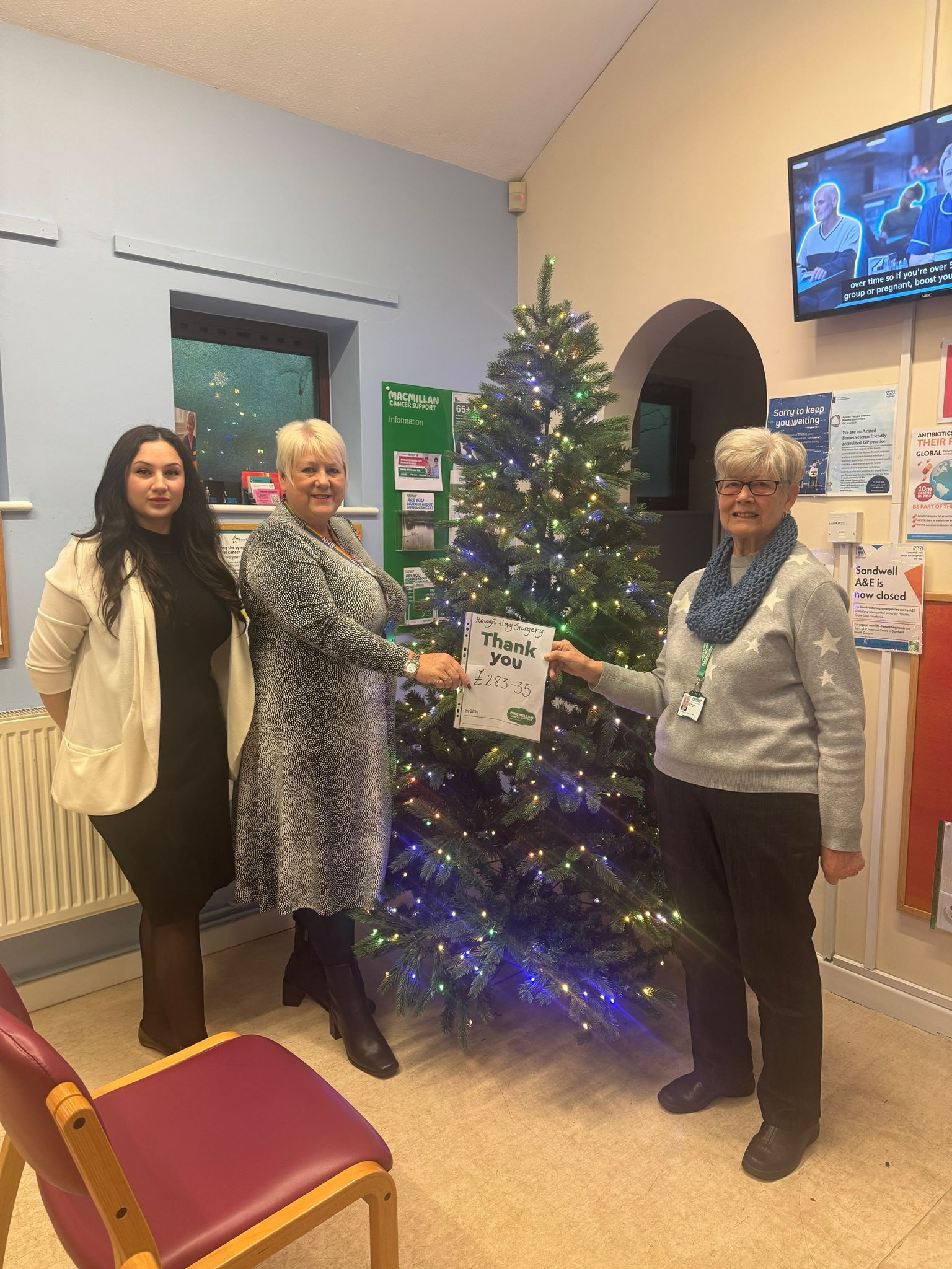 3 members of the surgery holding the thank you from Macmillan