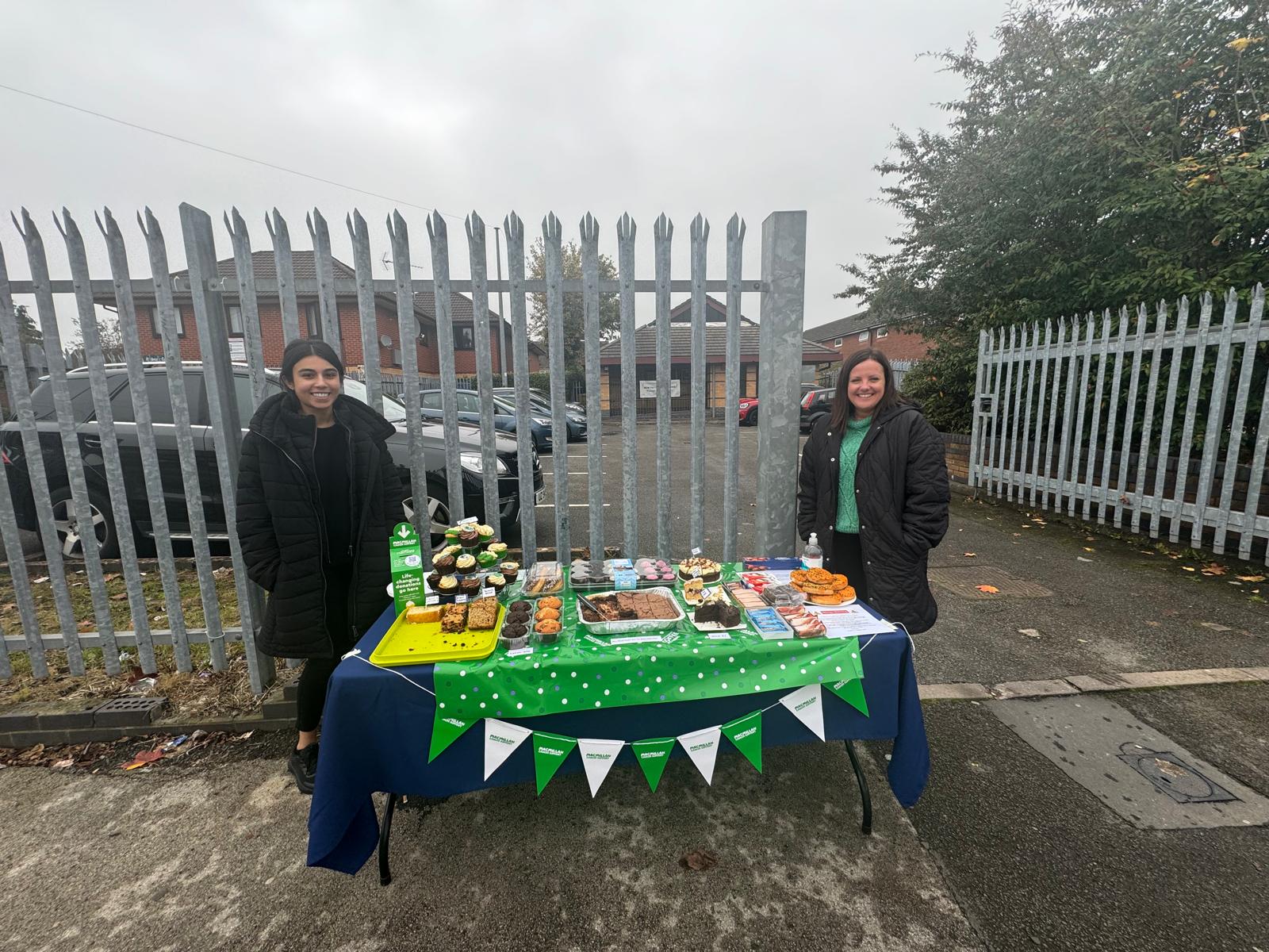 2 members of staff stood with a cake table outside the surgery